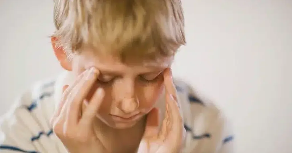 A man stands in the center of a room, holding his head in discomfort, indicating he has a Vertigo
