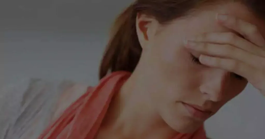 A woman sits with her head in her hands, expressing distress or frustration