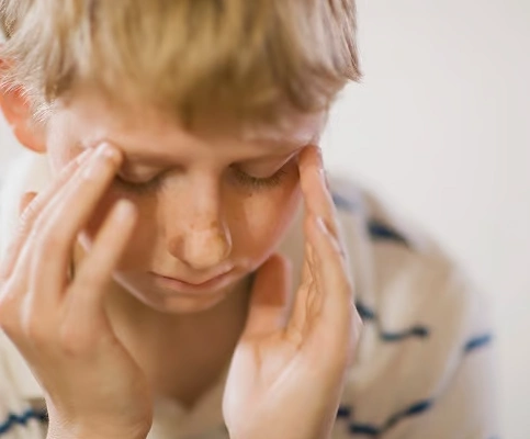A man stands in the center of a room, holding his head in discomfort, indicating he has a Vertigo